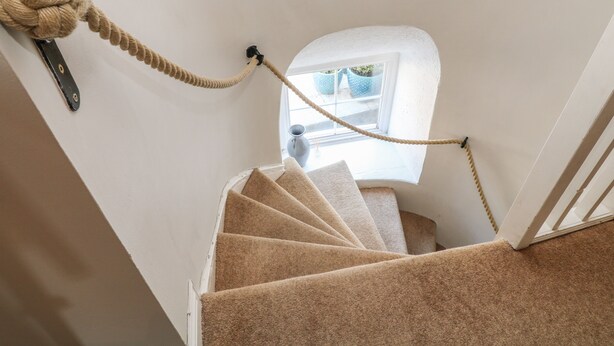 A staircase with a rope toy, a window, and a vase. - Old Town House (Dawlish)