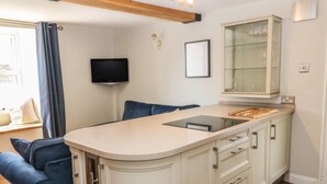 A modern kitchen with a central island, a built-in TV, and a glass cabinet. - Old Town House (Dawlish)