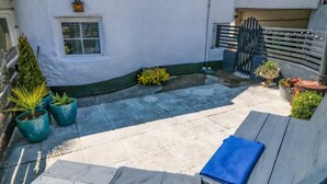 A courtyard with a wooden bench, potted plants, a small garden, and a gate. - Old Town House (Dawlish)