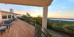 Eine Holzterrasse mit Gartenmöbeln, mit Blick auf eine malerische Landschaft mit Bäumen und einem Gewässer.