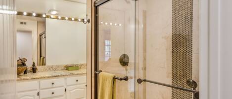 A bathroom with a glass shower enclosure, a vanity with a mirror, and a towel rack.