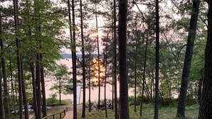 Eine Holzterrasse führt zu einer Sitzgruppe mit Blick auf einen See und einen Sonnenuntergang.