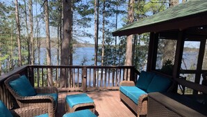 Eine Terrasse mit Korbmöbeln und einem überdachten Bereich mit Blick auf einen See.
