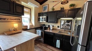 Eine moderne Küche mit dunklen Schränken, Edelstahlgeräten und einer Holz Arbeitsplatte.