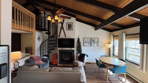 Ein Wohnzimmer mit Kamin, einer Treppe, einem Fernseher und einem Essbereich.