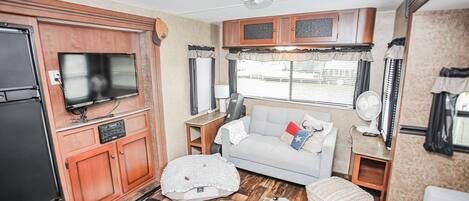 Ein kompaktes Wohnmobil-Interieur mit einer Küchenzeile, einem Fernseher, einer Sitzecke und einem Cowhide-Teppich.