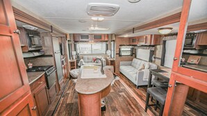 Een compact camperinterieur met een keuken, eethoek en een kleine zithoek.