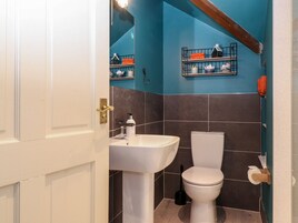 Un baño con un lavamanos blanco, un inodoro y una pared azul.