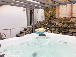Un jacuzzi con pared de piedra y escalones que conducen a una puerta.