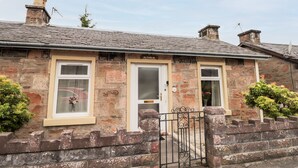 A stone house with three doors, a brick wall, and a metal gate. - Alturlie (Inverness)