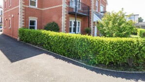 A two-story brick house with a balcony, a hedge in front, and a clear sky. - Marina Reach (Weymouth)