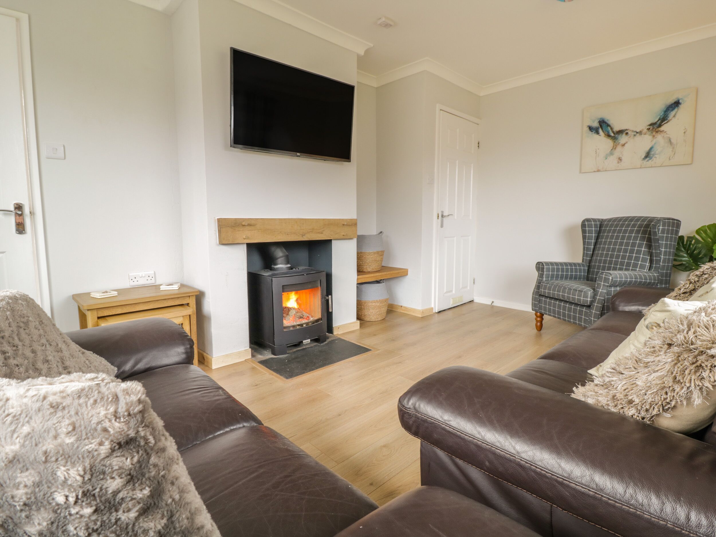 A living room with a fireplace, leather sofas, a television, and a painting on the wall.