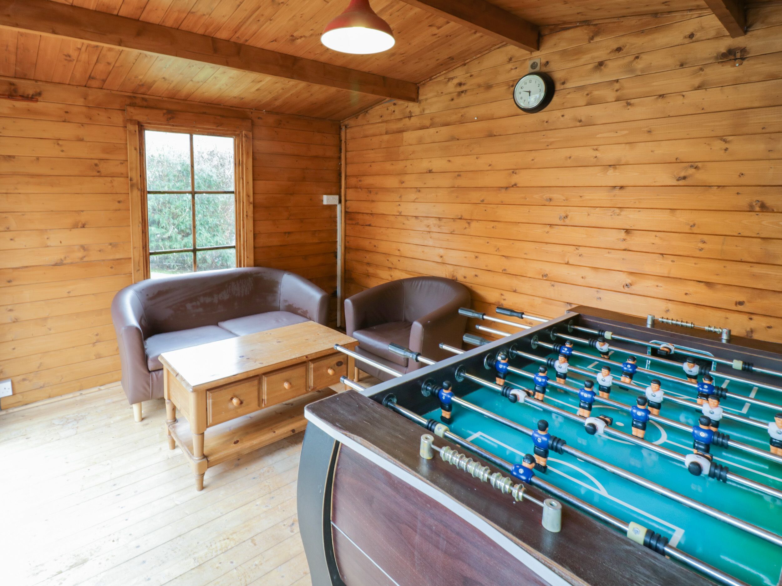 Una habitación de madera con una mesa de fútbol de mesa, un sofá y una pequeña mesa.