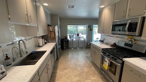 A modern kitchen with stainless steel appliances, a large window, and a view of the outdoors.