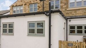 A building with a stone facade, multiple windows, and a wooden gate labeled "Holiday House". - Holida Hoose (Belford)