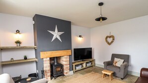 A living room with a fireplace, a television, and seating areas. - Holida Hoose (Belford)