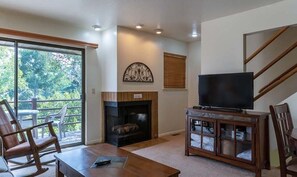 Cozy living room with a fireplace, TV, and sliding glass door to an outdoor area.