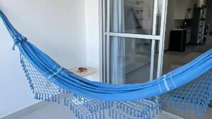 A hammock in a room with a glass door leading to a kitchen area. - Beautiful apartment in Bacutia (Guarapari)