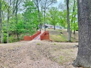 Cross a wooden bridge into a serene forested area.