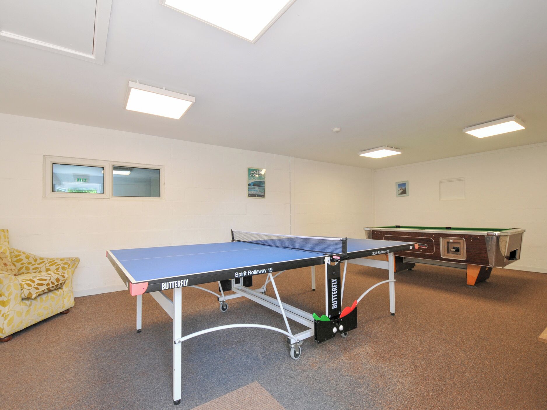 Et værelse med et pingpongbord, et billardbord og en sofa.