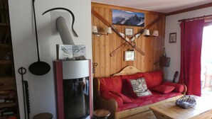 Una sala de estar acogedora con chimenea, paredes de madera, un sofá rojo y una mesa de centro de madera.