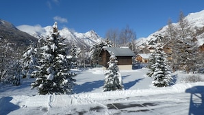 Paisaje nevado de montañas con cabañas de madera y árboles cubiertos de nieve.