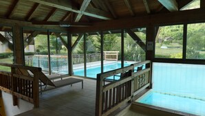 Zona de piscina exterior cubierta con barandillas de madera y vistas a una zona residencial.