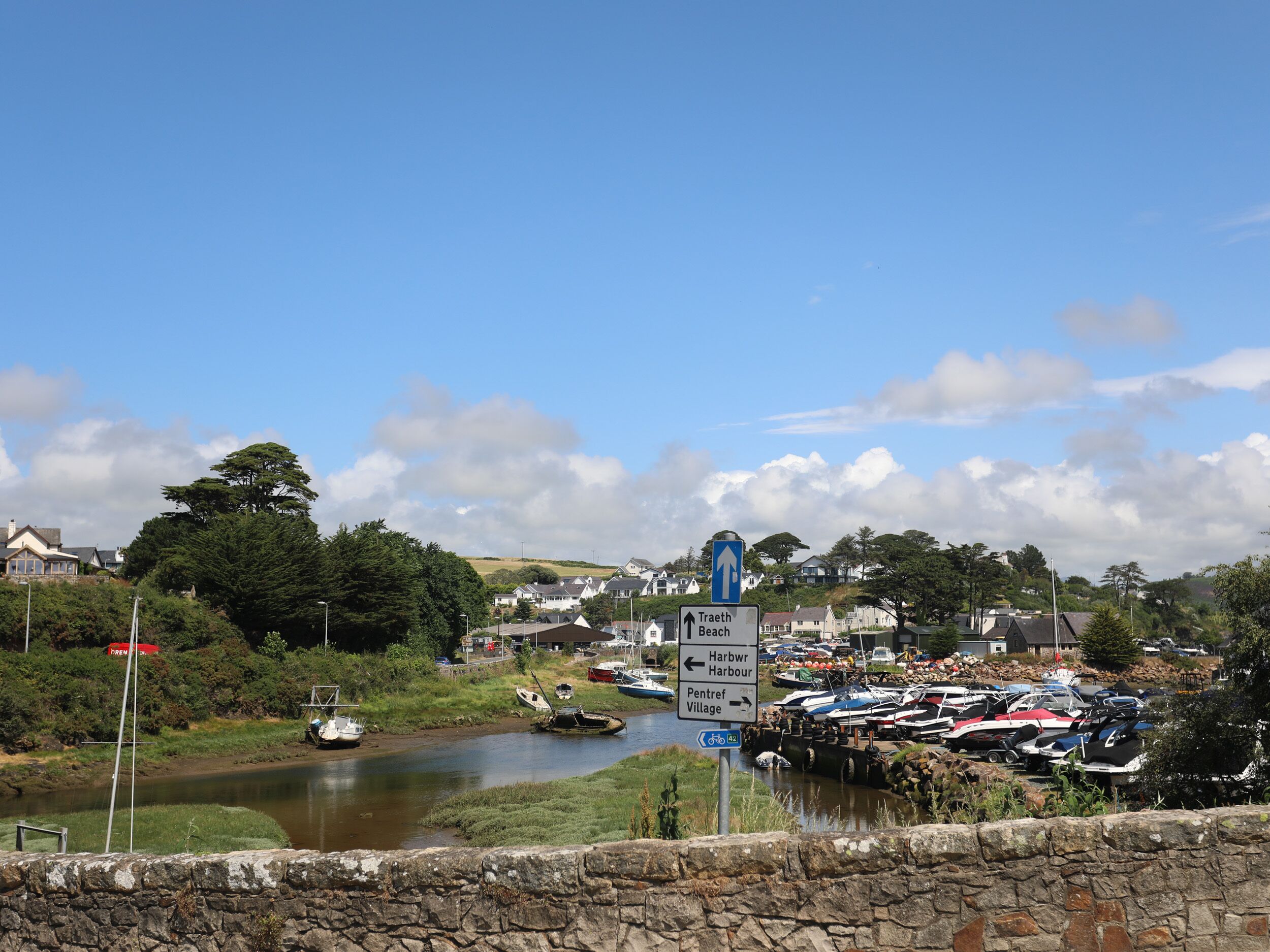 A coastal town with a marina, stone walls, and directional signs.