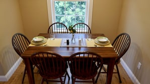A dining table set for four with a vase of flowers, plates, and cutlery.