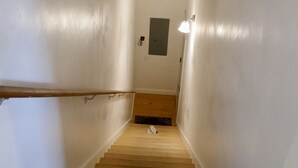 A wooden staircase with white walls and a light fixture at the top.