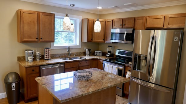 A modern kitchen with wooden cabinets, stainless steel appliances, granite countertops, and a large island.
