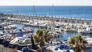 A marina with numerous boats docked, a waterfront promenade, and palm trees. - Home2Book Comfy Beachfront Radazul (Radazul)