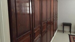 A wooden wardrobe with multiple doors, a small table, and a wall-mounted air conditioning unit. - BIG VILLA WITH A PARKING  (Site archéologique de Carthage)