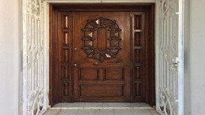 A wooden door with intricate carvings and a metal gate on either side. - BIG VILLA WITH A PARKING  (Site archéologique de Carthage)