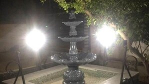 A multi-tiered fountain with water cascading down, surrounded by a square base and two metal stands. - BIG VILLA WITH A PARKING  (Site archéologique de Carthage)