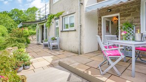 Un patio con una mesa y sillas, una terraza de madera y plantas en macetas.