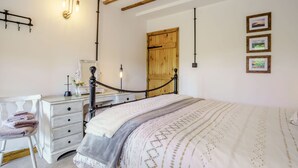 Un dormitorio con cama, cómoda, silla y puerta de madera.