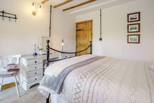 Un dormitorio con cama, cómoda, silla y puerta de madera.
