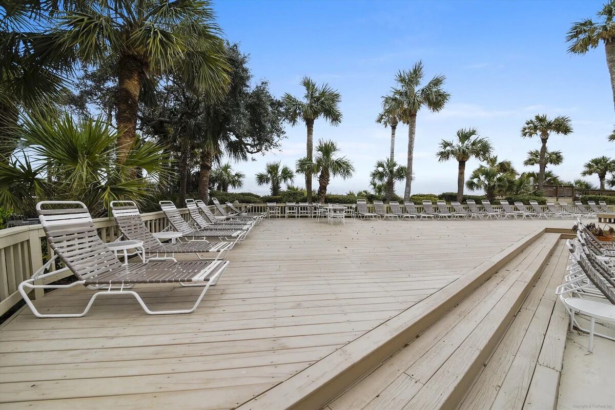 Une terrasse en bois avec des chaises longues et des palmiers.