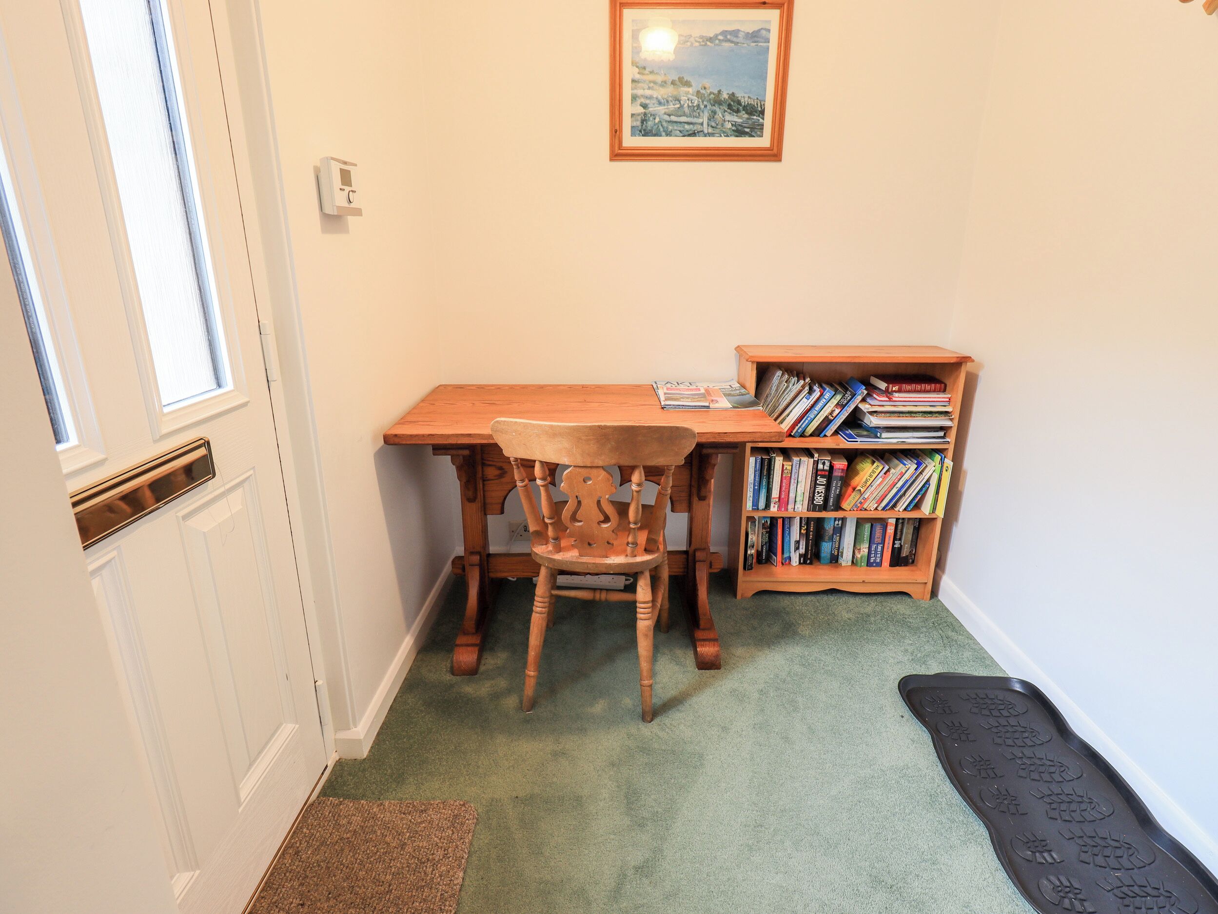 A room with a wooden desk, a chair, a bookshelf, and a door with a window.