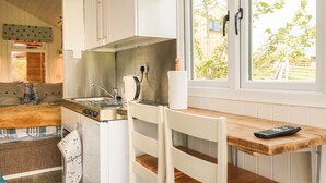 A kitchen with a wooden countertop, a sink, a stove, and a window with a view of greenery. - Langdale Lodge (Okehampton)