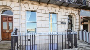 A building with a stone facade, numbered doors, and a metal fence. - Bliss On The Bay (Weymouth)
