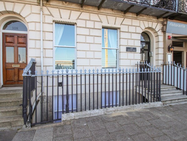 A building with a stone facade, numbered doors, and a metal fence.