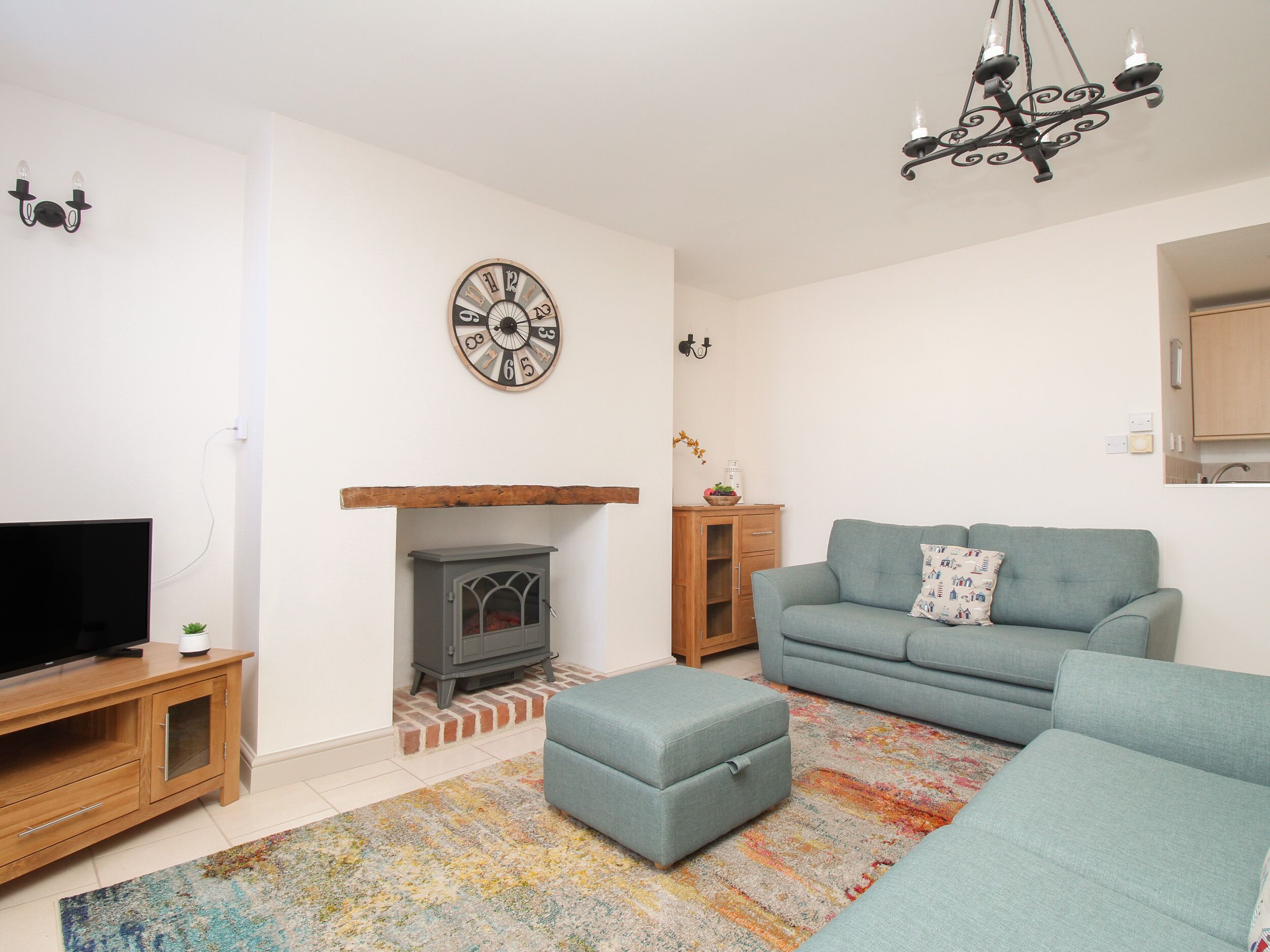A living room with a television, a fireplace, a sofa, and a patterned rug.