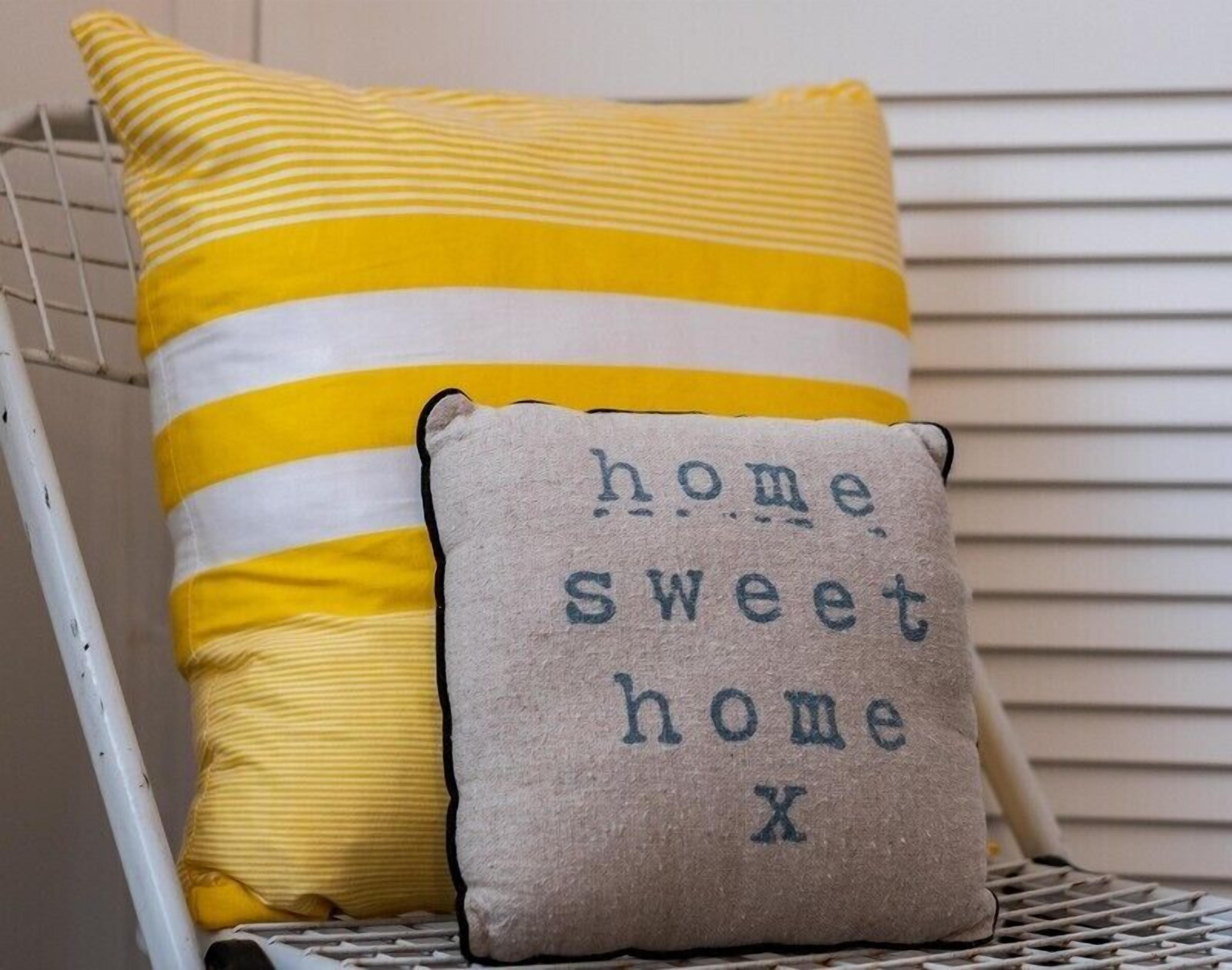 A chair with a yellow and white striped pillow and a smaller pillow with the text "home sweet home."