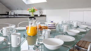 A breakfast table set with white dishes, glasses, and a pitcher of orange juice. - 2 Church Hill House (Salcombe)