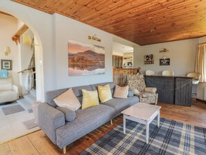A cozy living room with a grey sofa, a coffee table, and a painting of a landscape.