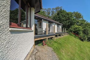 Una casa moderna con balcón, ventanas amplias y jardín con césped.