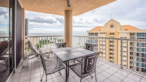 Een balkon met een tafel en stoelen, met uitzicht op een stadsbeeld en de oceaan.