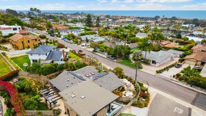 A residential area with houses, a stop sign, and a clear view of the ocean.